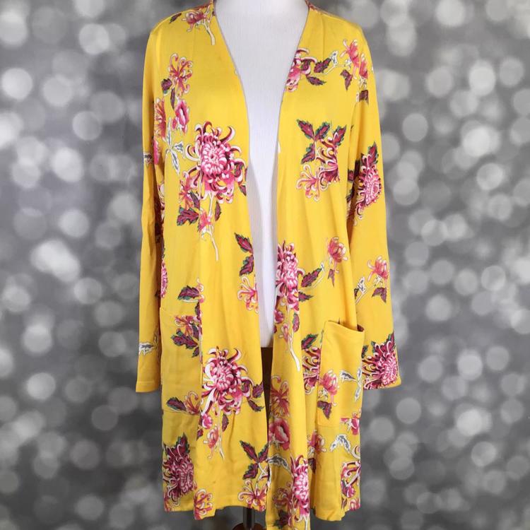 Front view of LuLaRoe Caroline cardigan displayed on mannequin featuring golden yellow background with pink floral pattern, open front design, and patch pockets