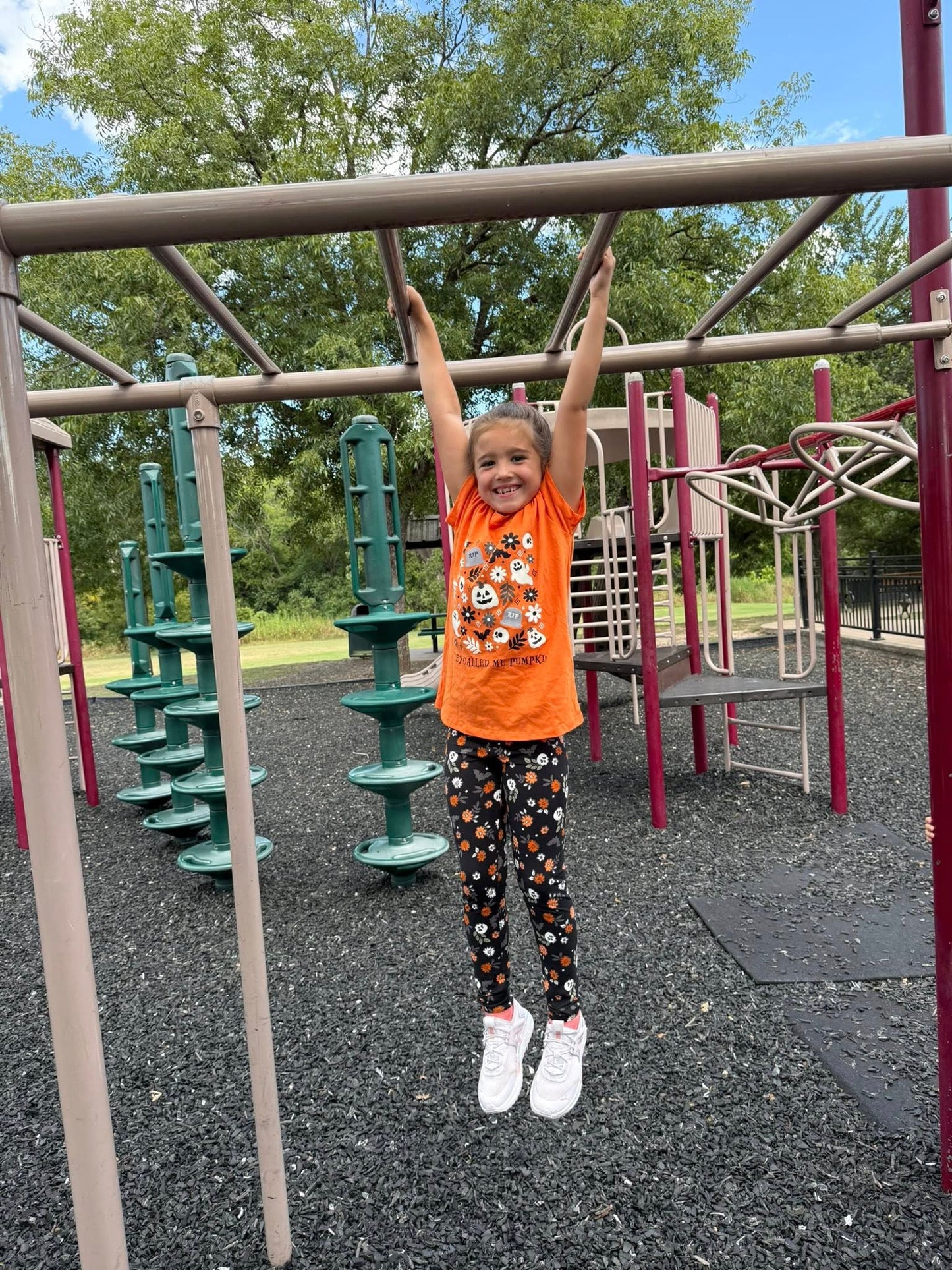 Child playing on playground equipment with colorful play structure in the background