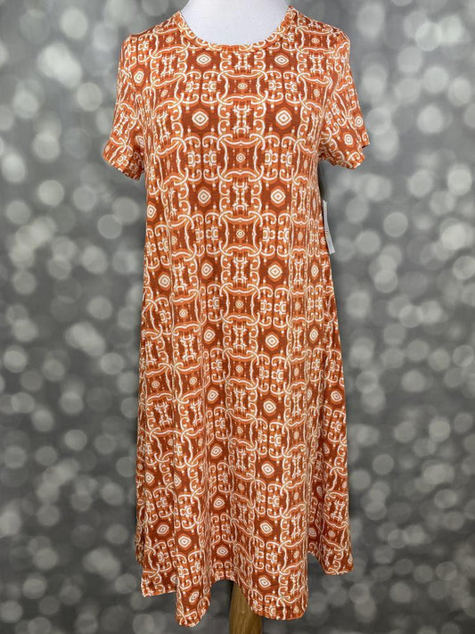 Front view of LuLaRoe Jessie dress on mannequin in terracotta orange geometric chain pattern with short sleeves, scoop neckline, and flowy swing fit