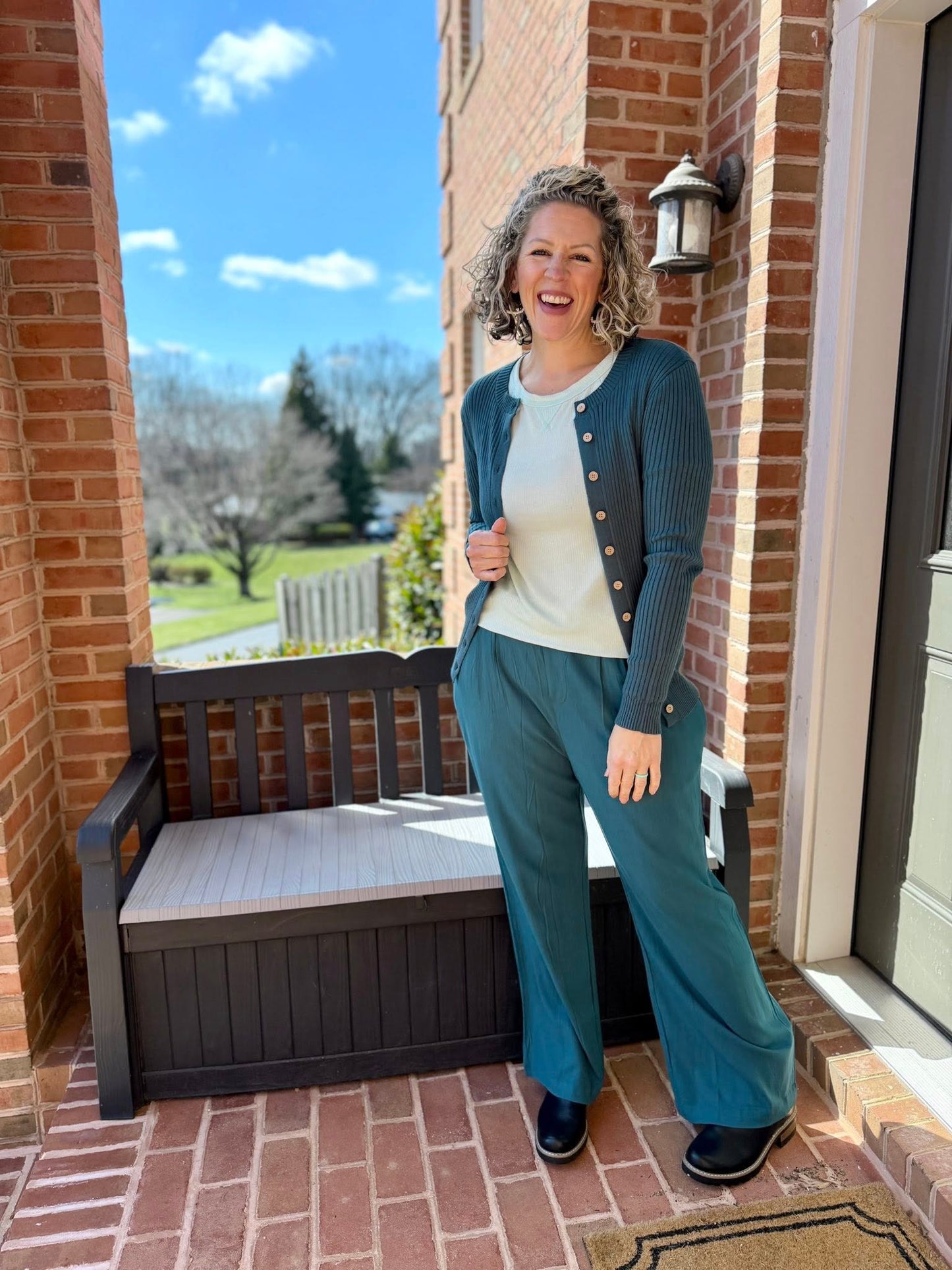 Woman standing on a porch with a bench and brick wall background