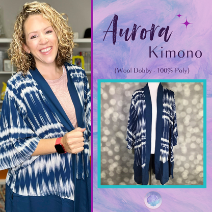 LuLaRoe Aurora Kimono in blue and white tie-dye waves displayed on a mannequin against a soft bokeh background. Lightweight open-front kimono with wide sleeves and deep navy trim in drapey Wool Dobby fabric.