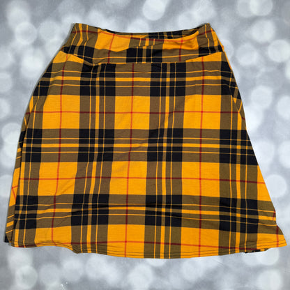 A yellow and black plaid skirt laid flat against a gray bokeh background.