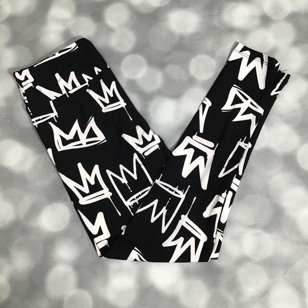 LuLaRoe leggings in Crown Street with black background, white graffiti-style crown pattern, and soft stretchy fabric on a blurred gray background