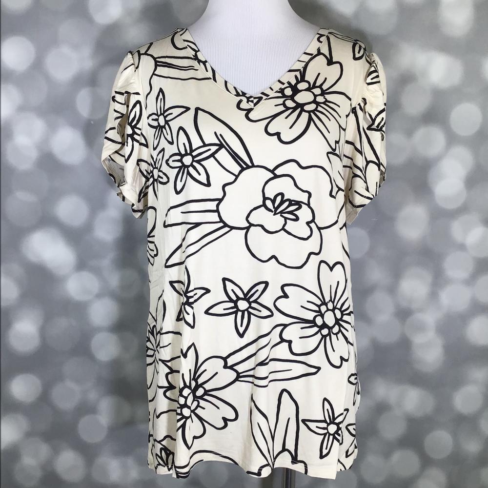 Cream LuLaRoe Remi top with bold black floral outlines, tulip sleeves, and V-neck, displayed on mannequin against a blurred gray background