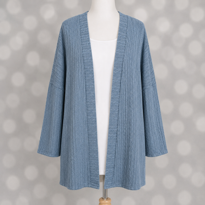 LuLaRoe Connie Lightweight Overlay in Solid Denim Blue featuring a lightweight cable knit texture, open front cardigan, relaxed fit, and long sleeves layered over a white ribbed tank.