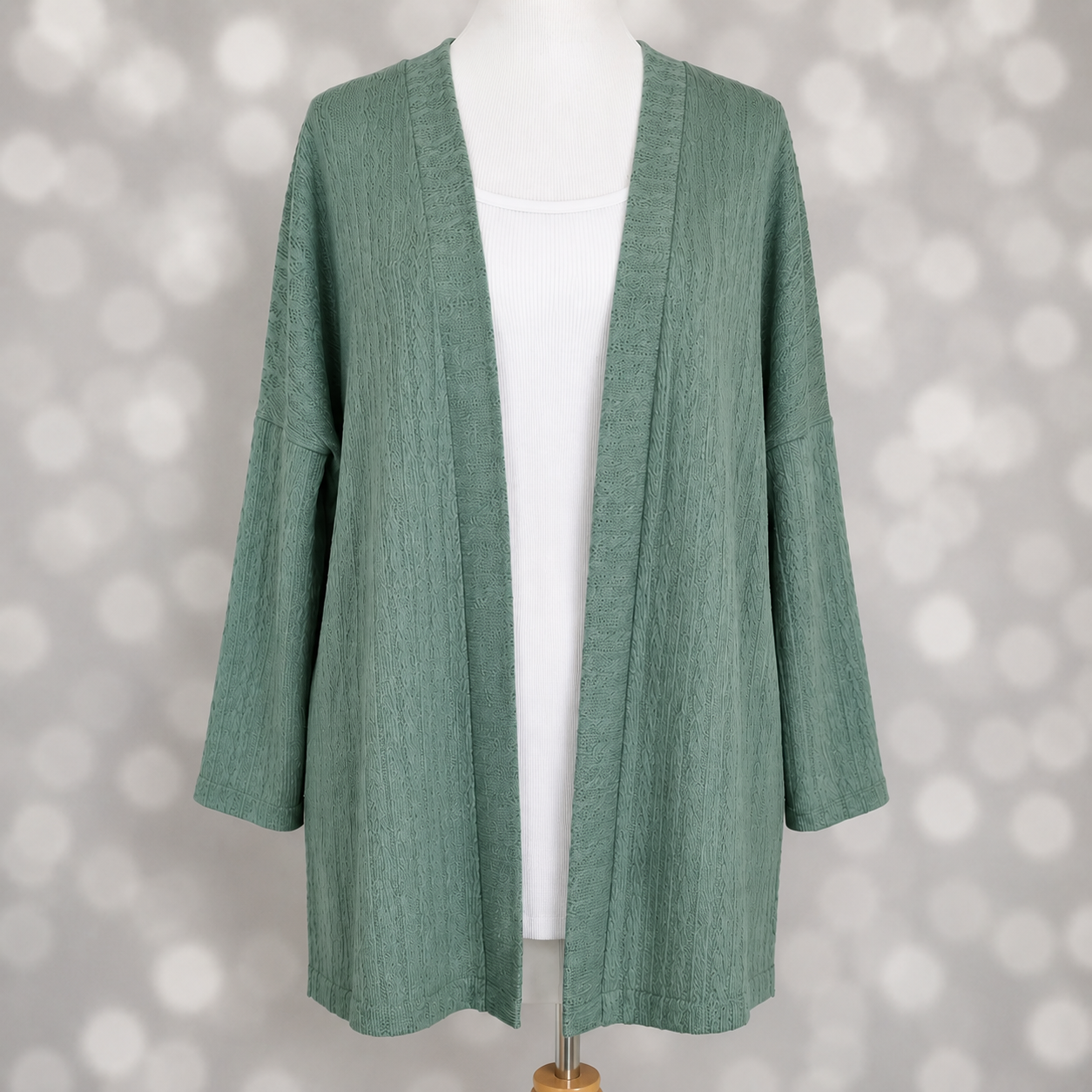 LuLaRoe Connie Lightweight Overlay in Solid Eucalyptus Green featuring a lightweight cable knit texture, open front cardigan, relaxed fit, and long sleeves layered over a white ribbed tank.