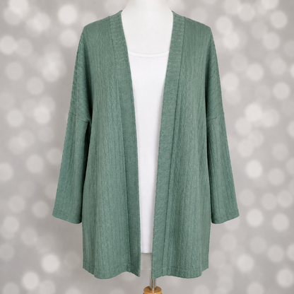 LuLaRoe Connie Lightweight Overlay in Solid Eucalyptus Green featuring a lightweight cable knit texture, open front cardigan, relaxed fit, and long sleeves layered over a white ribbed tank.