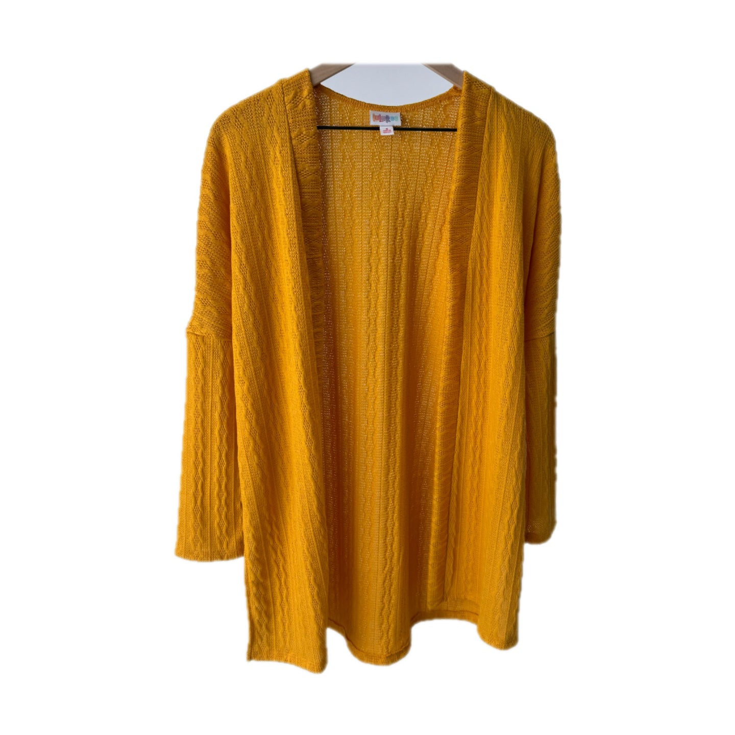 LuLaRoe Connie Lightweight Overlay in Solid Mustard featuring a lightweight cable knit texture, open front cardigan, relaxed fit, and long sleeves layered over a white ribbed tank.