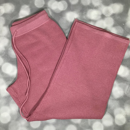 Flat lay of the Carma Bottom in a solid rosy blush pink color, showing the ribbed waistband with drawstring, relaxed full-length leg, and soft micro rib sweater knit texture on a gray bokeh background