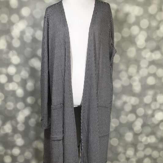 Front view of LuLaRoe Caroline Cardigan on mannequin featuring black and white houndstooth print, open front, and cropped sleeve length against a blurred background