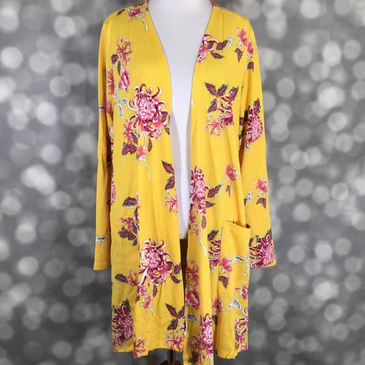 Front view of LuLaRoe Caroline cardigan displayed on mannequin featuring golden yellow background with pink floral pattern, open front design, and patch pockets