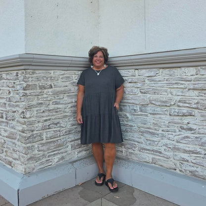 Person standing in front of a building with stone base and light fixtures