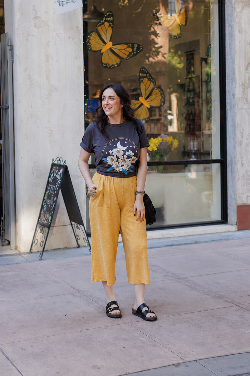 Woman standing on a sidewalk in front of a store with butterfly decorations.