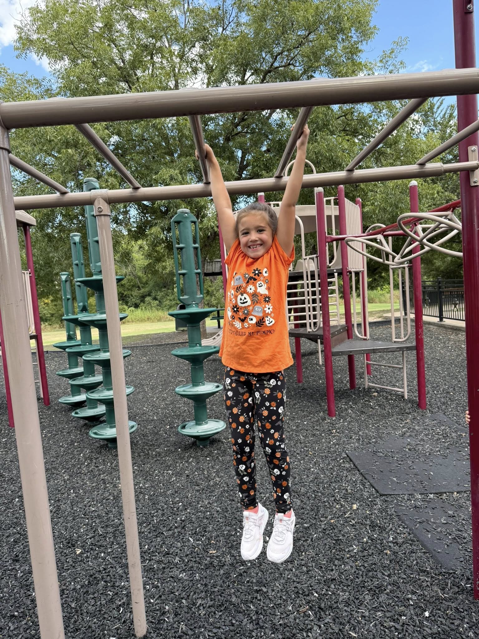 Child playing on playground equipment with colorful play structure in the background