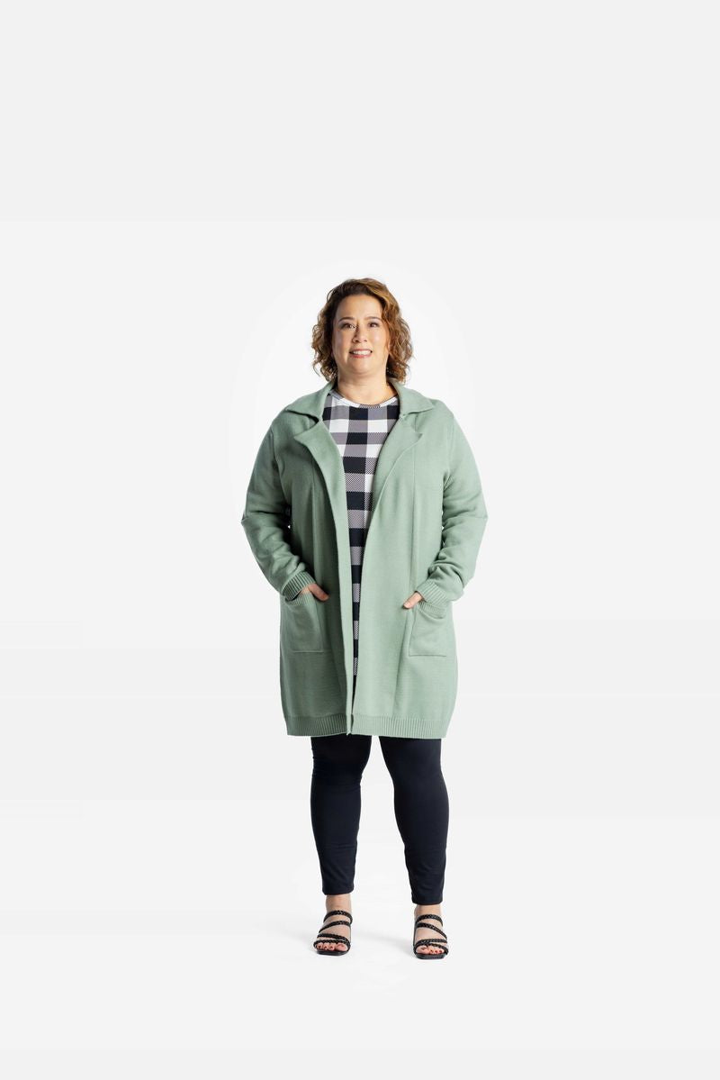 Model wearing a solid soft sage green Laura lapel open cardigan with front pockets on a white background
