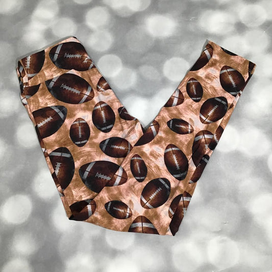 Flat lay of LuLaRoe leggings in brown background with novelty football print, yoga waistband, and ankle-length silhouette