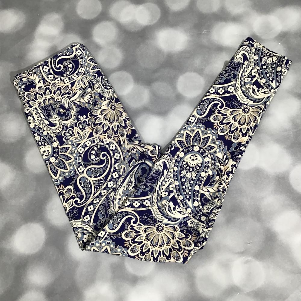 Flat lay of LuLaRoe leggings in navy background with intricate cream and blue paisley floral print, yoga waistband, and ankle-length cut