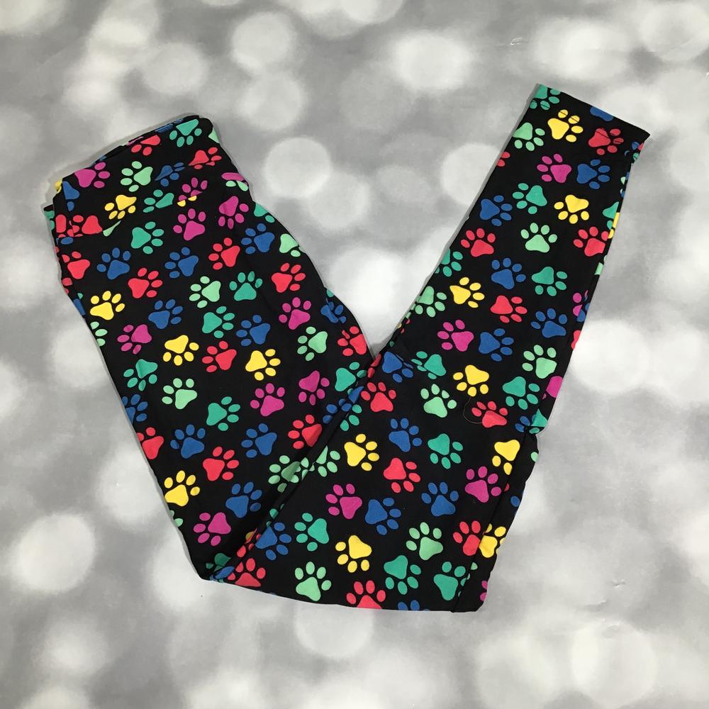 Flat lay of LuLaRoe leggings in black with multicolor paw print design in rainbow shades, yoga waistband, and ankle-length fit