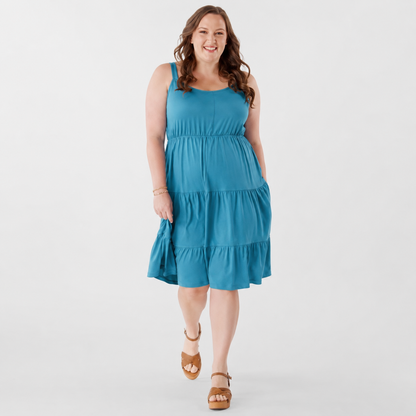 Plus-size woman modeling the LuLaRoe Amanda Dress in Solid Ocean Teal, featuring a vibrant teal blue-green sleeveless tiered midi silhouette with a relaxed flowy fit and casual resort-inspired styling photographed against a light neutral studio background.
