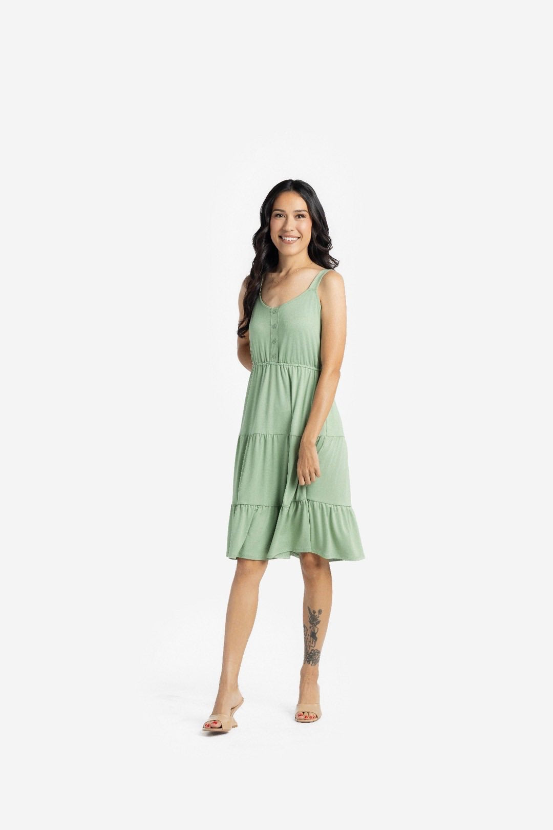 Woman modeling the LuLaRoe Amanda Dress in Solid Soft Sage, featuring a muted sage green sleeveless tiered midi silhouette with a relaxed feminine fit photographed against a light neutral studio background.