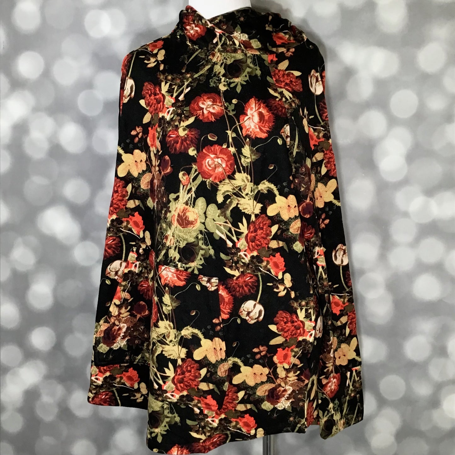 LuLaRoe Amber Hoodie in Midnight Garden Noir featuring black background with red and gold floral print, hooded neckline, and kangaroo pocket with arelaxed fit, long sleeves, soft stretch fabric on a mannequin against a gray background