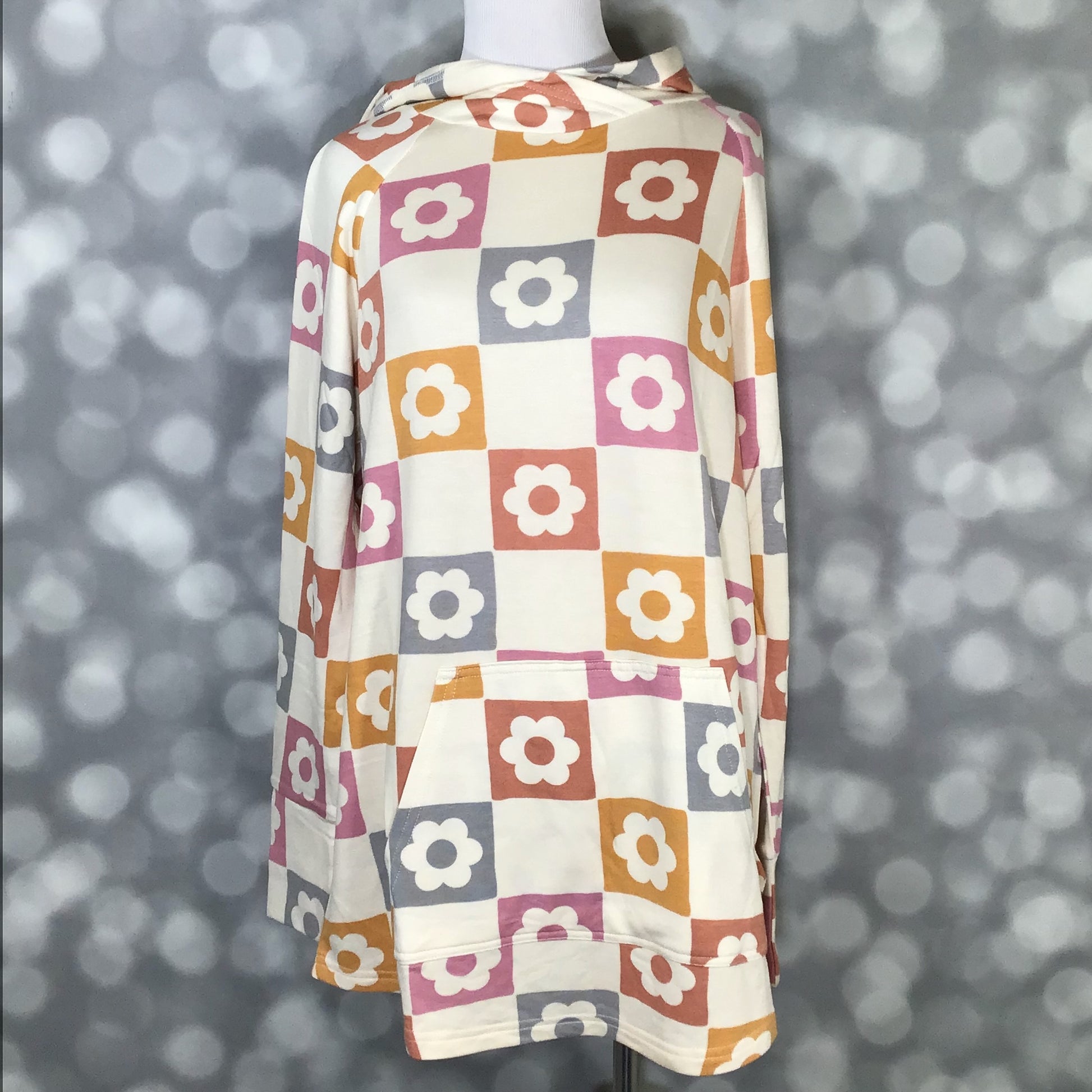 LuLaRoe Amber Hoodie Retro Petal Checker with ivory background and checkerboard floral squares in rust, mustard, pink, and gray, showing long sleeves, hood, and kangaroo pocket with front view on a mannequin with a gray background