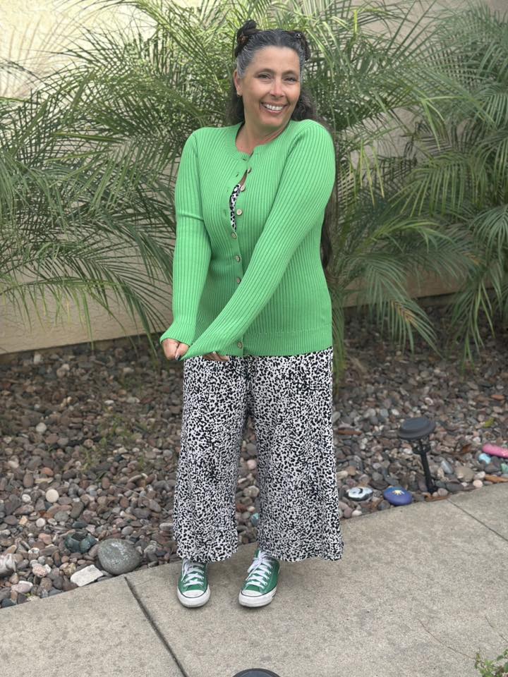 LuLaRoe Becky cardigan in solid fresh clover green rib knit with wooden buttons and fitted silhouette on a woman wearing  patterned pants standing outdoors with plants in the background