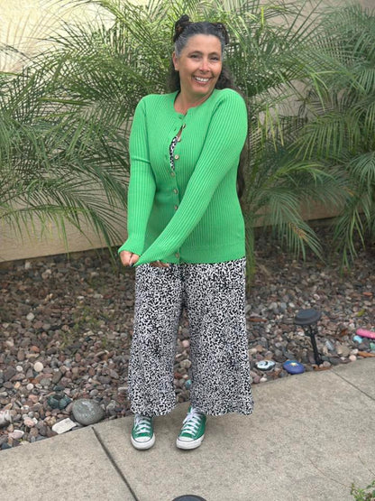 LuLaRoe Becky cardigan in solid fresh clover green rib knit with wooden buttons and fitted silhouette on a woman wearing  patterned pants standing outdoors with plants in the background