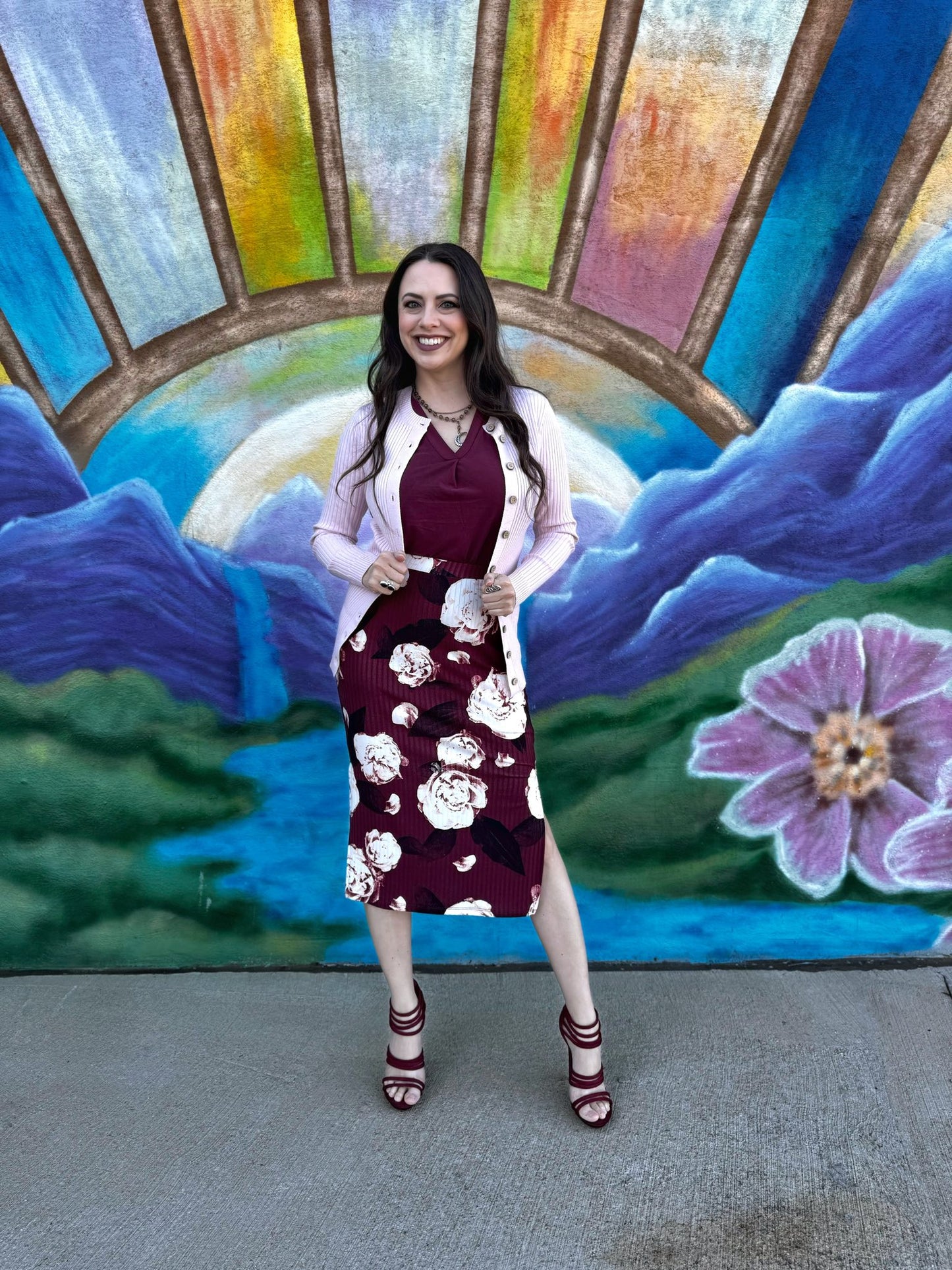 LuLaRoe Becky cardigan in solid soft ballet pink rib knit with wooden button front closure and fitted silhouette on a woman posing in front of a colorful mural with floral design