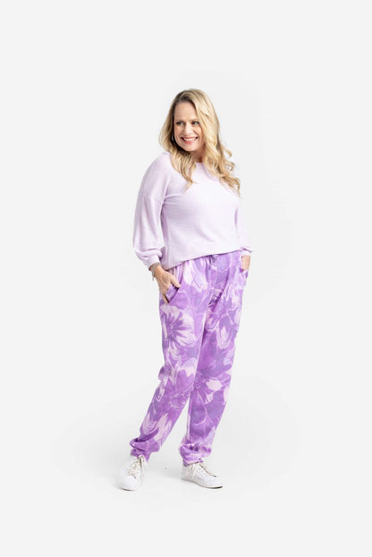 LuLaRoe Boyfriend Joggers in a purple watercolor floral print worn by a model. Relaxed-fit joggers with drawstring waist, cuffed ankles, and soft Ponte fabric.