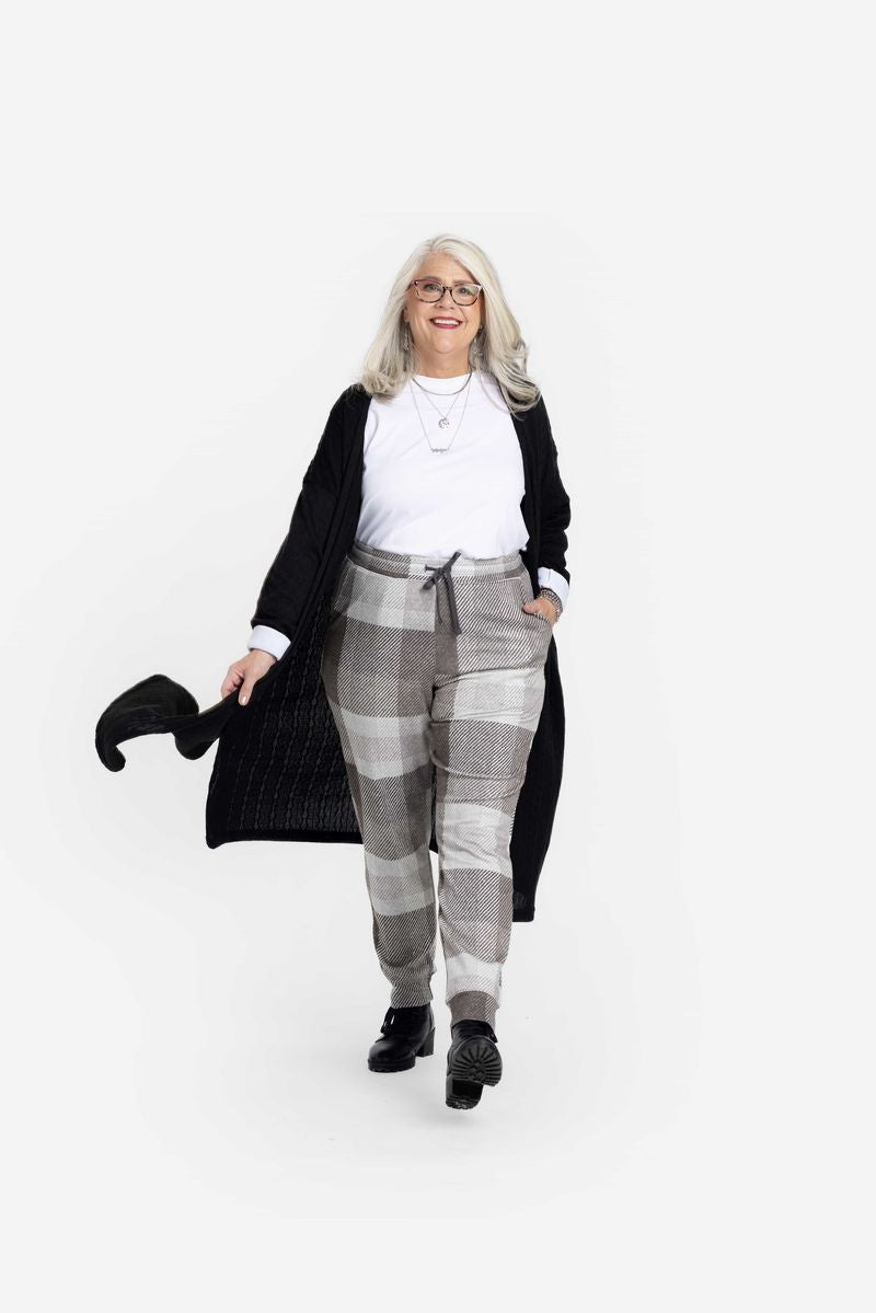 LuLaRoe Boyfriend Joggers in a soft gray neutral plaid print, worn by a model with a white tee and black cardigan. Relaxed-fit joggers with drawstring waist and cuffed ankles.