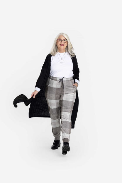 LuLaRoe Boyfriend Joggers in a soft gray neutral plaid print, worn by a model with a white tee and black cardigan. Relaxed-fit joggers with drawstring waist and cuffed ankles.