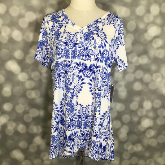 LuLaRoe Christy T featuring cobalt blue porcelain-inspired floral scrollwork on a white background with a relaxed V-neck silhouette displayed on a mannequin against a silver bokeh backdrop.