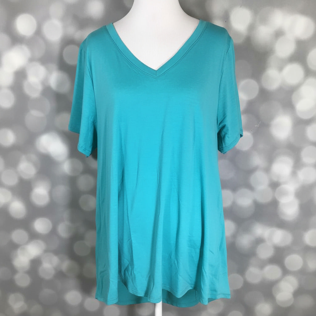 LuLaRoe Christy T in Solid Aqua Lagoon featuring a bright aqua blue color with a relaxed V-neck silhouette displayed on a mannequin against a silver bokeh background.