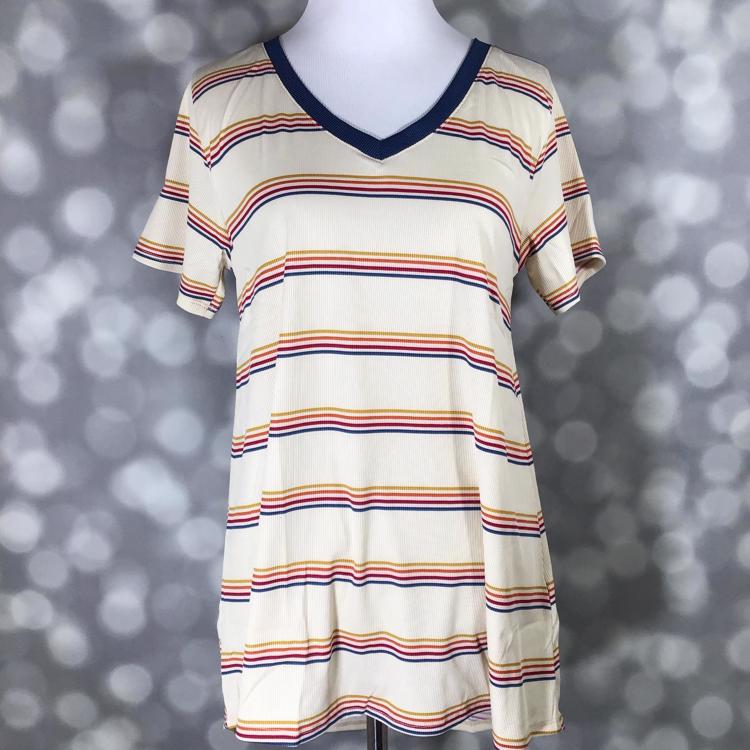 LuLaRoe Christy T featuring retro multicolor horizontal stripes in navy, mustard, coral, and rust on an ivory background with a relaxed V-neck swing silhouette displayed on a mannequin against a silver bokeh backdrop.