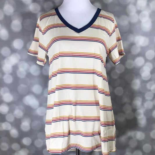 LuLaRoe Christy T featuring retro multicolor horizontal stripes in navy, mustard, coral, and rust on an ivory background with a relaxed V-neck swing silhouette displayed on a mannequin against a silver bokeh backdrop.
