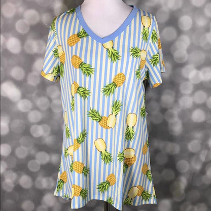 LuLaRoe Christy tee with blue and white vertical stripes and yellow pineapple print, v-neckline, short sleeves, relaxed flowy fit, displayed on mannequin