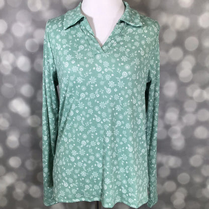 Green floral long-sleeve blouse on a mannequin against a blurred background