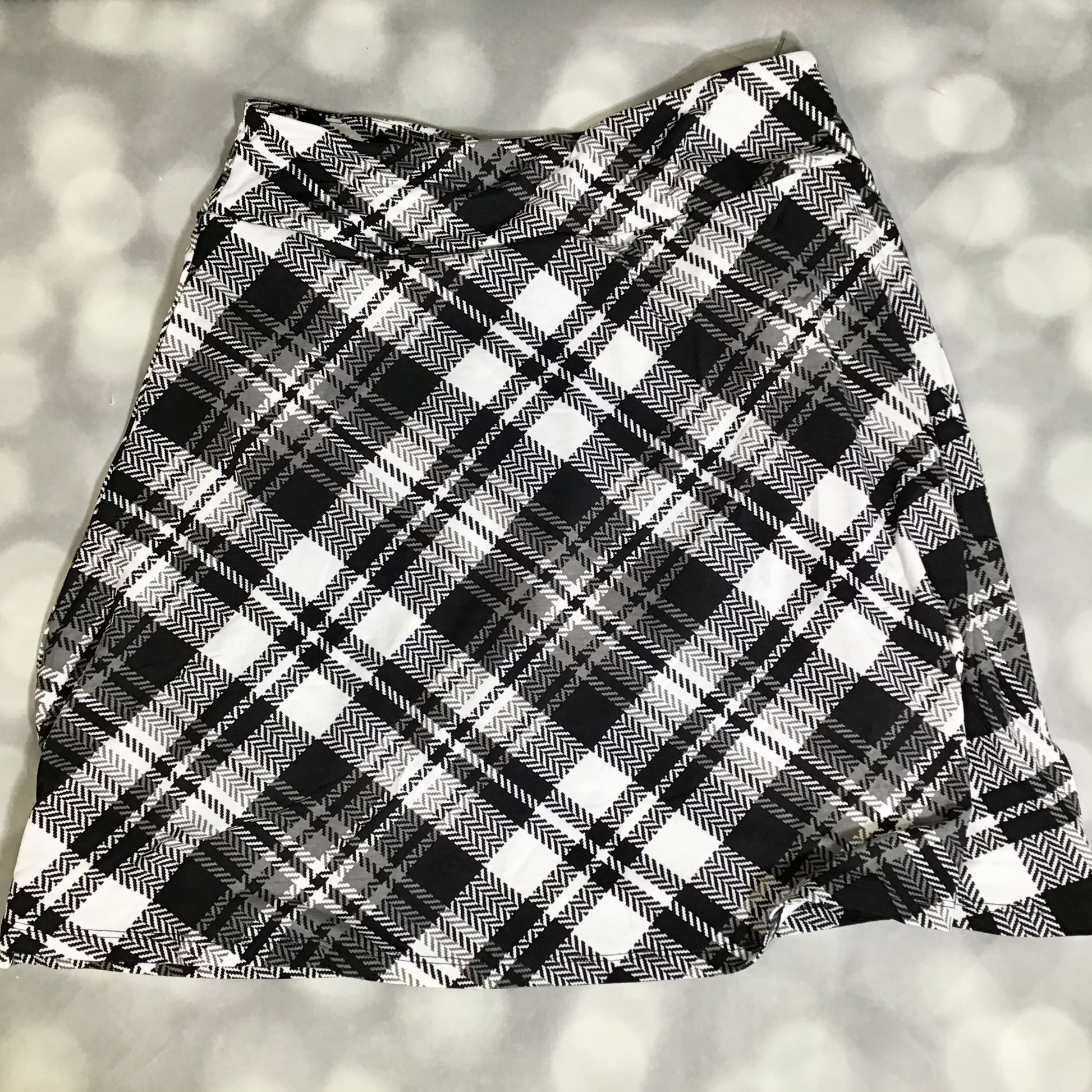 LuLaRoe Eileen skort in black and ivory plaid pattern featuring a classic tartan-style design with a flared silhouette and built-in shorts on a light gray background