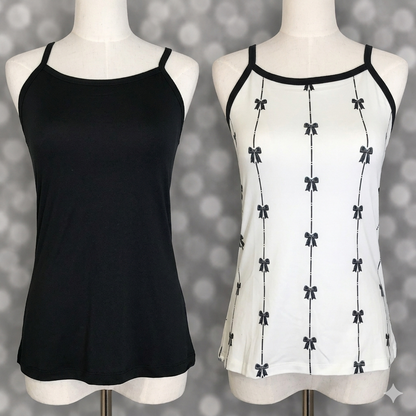Two LuLaRoe Essential camis photographed on mannequin torsos including a solid black cami and a white camisole with vertical black ribbon bow stripe print on a soft gray blurred background.