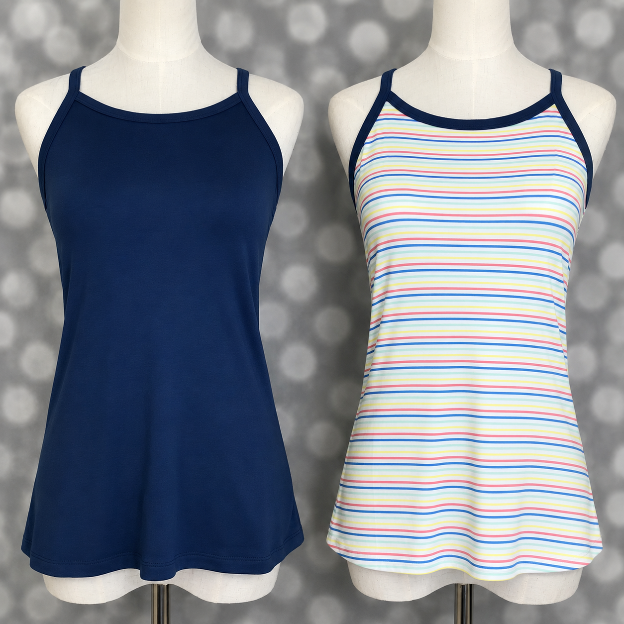 LuLaRoe Essential camis displayed side by side on mannequin forms featuring a solid navy blue camisole and a white pastel rainbow stripe print cami with pink, yellow, blue, and mint stripes against a gray bokeh studio background.