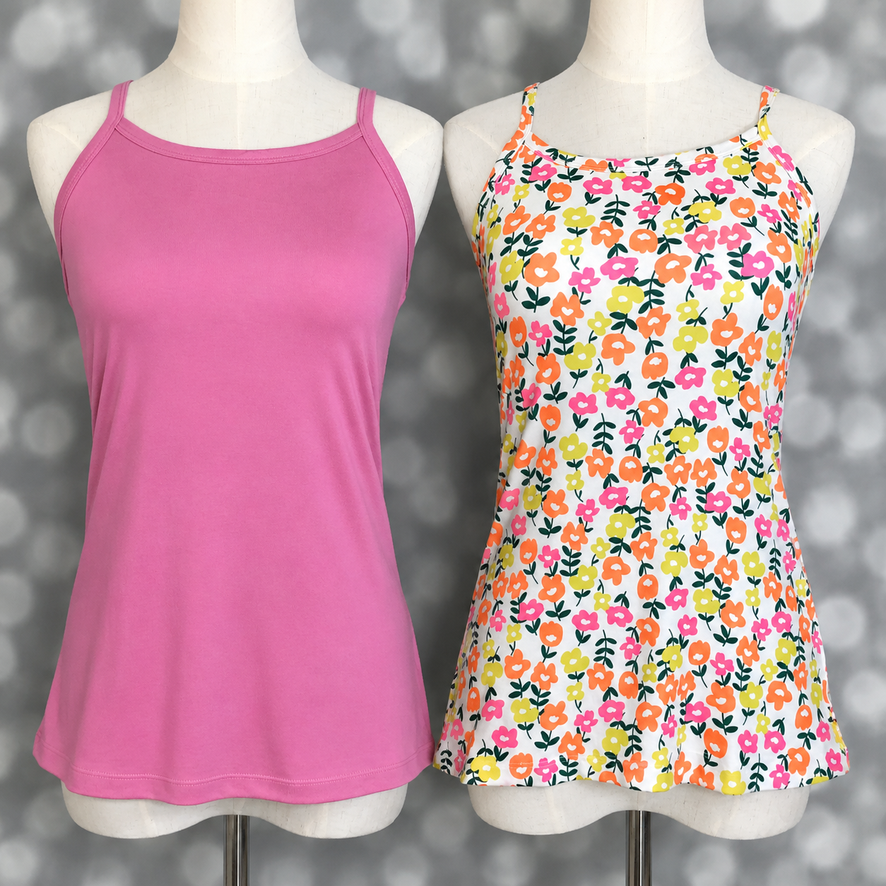 LuLaRoe Essential camis displayed on mannequin forms featuring a solid pink camisole and a white retro ditsy floral print cami with orange, yellow, and pink flowers against a gray bokeh background.