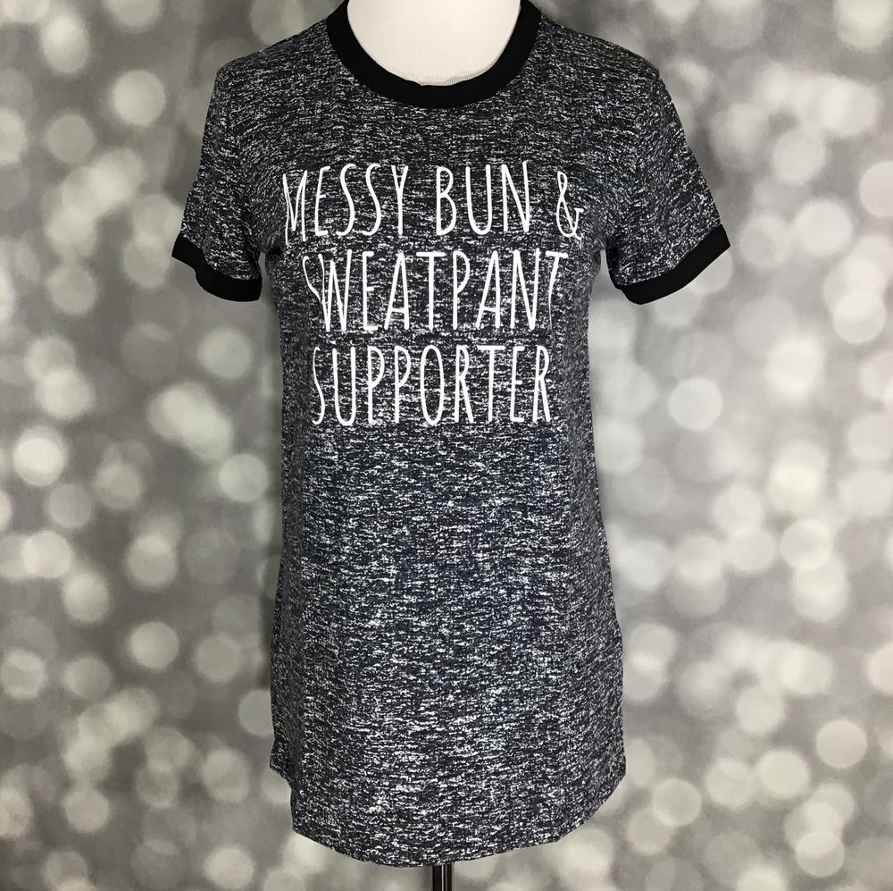 LuLaRoe heathered black graphic tee with “Messy Bun & Sweatpant Supporter” slogan in white lettering on a blurred background