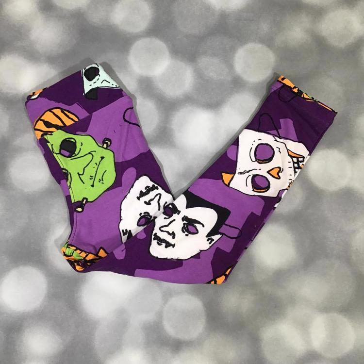 LuLaRoe Halloween leggings in purple featuring classic monster faces in green, white, and orange with spooky details.
