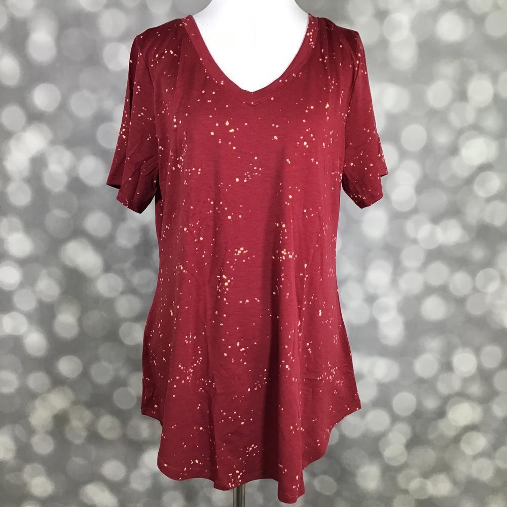 LuLaRoe Iris Tee in Crimson Stardust featuring a rich crimson red background with ivory speckled abstract star-like accents, relaxed tunic silhouette, rounded v-neck, short sleeves, and curved shirttail hem.