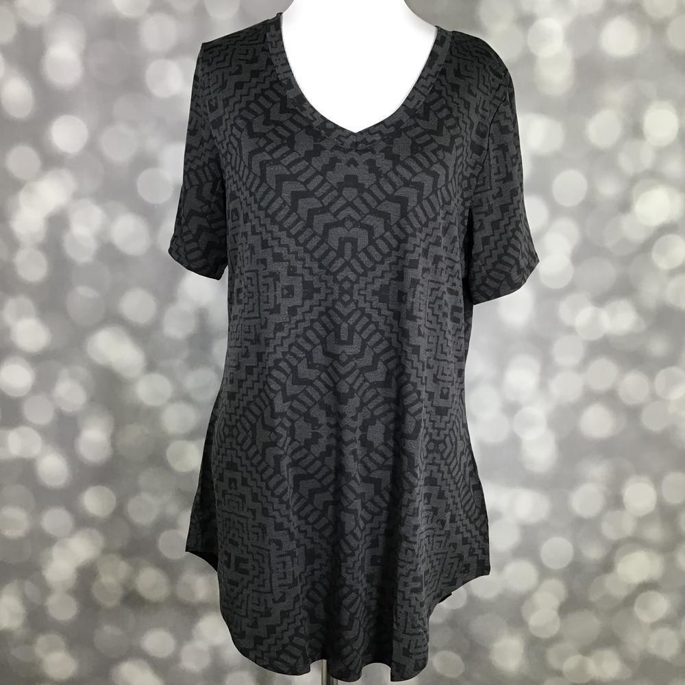 LuLaRoe Iris Tee in Shadow Mesa featuring a charcoal gray and black geometric tribal-inspired pattern, rounded v-neckline, relaxed sleeves, tunic-length silhouette, and curved shirttail hem.