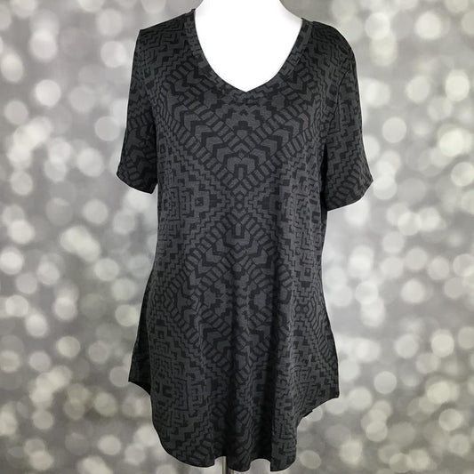 LuLaRoe Iris Tee in Shadow Mesa featuring a charcoal gray and black geometric tribal-inspired pattern, rounded v-neckline, relaxed sleeves, tunic-length silhouette, and curved shirttail hem.