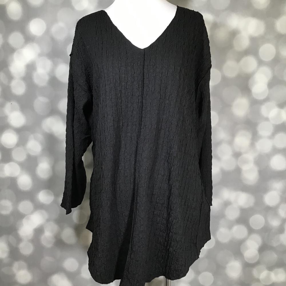 LuLaRoe Jolene V-neck tunic in solid black bubble jacquard fabric long sleeve relaxed-fit tunic with high-low hem and gauze-like texture displayed on mannequin against a blurred gray background