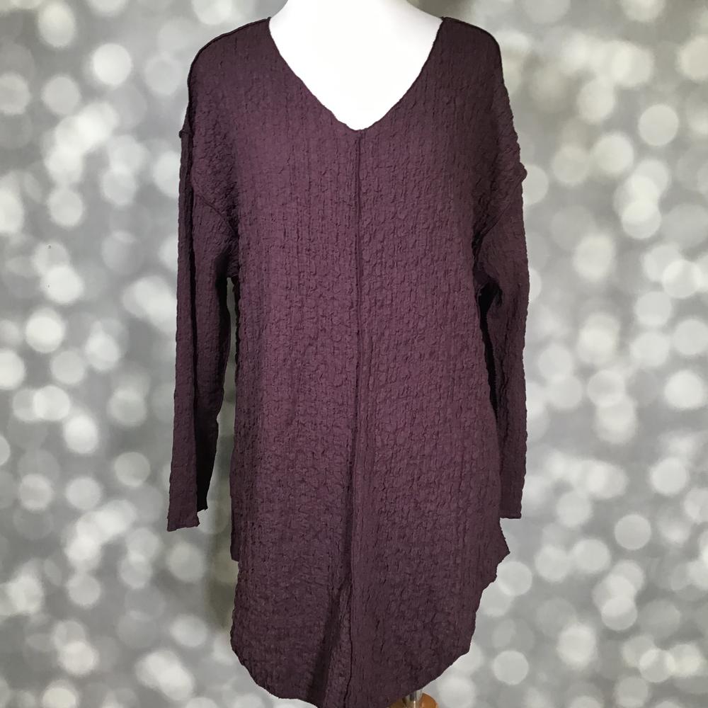LuLaRoe Jolene V-neck tunic top in solid plum wine bubble jacquard fabric, displayed on a mannequin. Long sleeve, relaxed-fit tunic with a gauze-like textured finish and high-low hem.