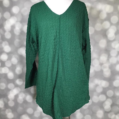 LuLaRoe Jolene V-neck tunic in solid rain forest green bubble jacquard fabric displayed on mannequin. LuLaRoe Jolene V-neck tunic top in solid green bubble jacquard fabric, long sleeve relaxed-fit tunic with gauze-like texture and high-low hem.